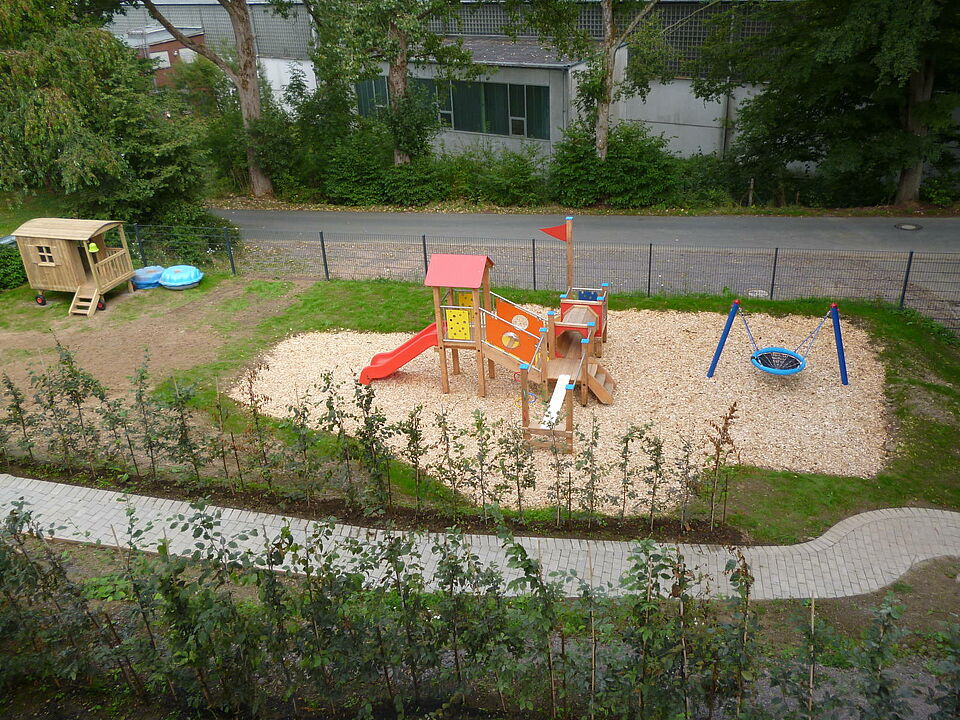 Rothemühler Knirpse_Außengelände Außengelände mit Spielplatz: Klettergerüst mit Rutsche, Schaukel, Sandmuscheln, Bauwagen aus Holz zum spielen