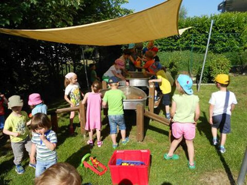 DRK-Familienzentrum Sternenland Kinder spielen unter einem Sonnensegel mit einer Wasserbahn