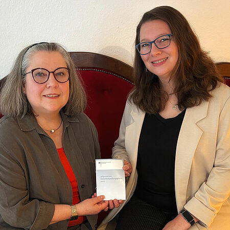 2025-08_Staffelübergabe_Antidiskriminierung K. Blumentrath, eine angehende Rentnerin und K. Schüren, Beraterin für Antidiskriminierung sitzen auf dem roten Sofa im DRK-Mehrgenerationenhaus in Olpe