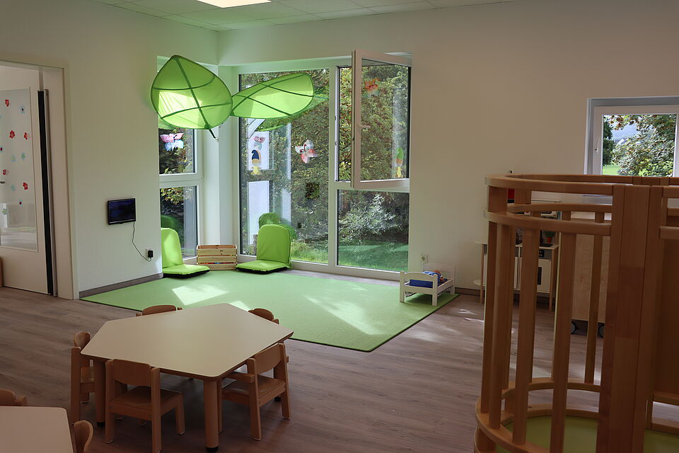 Peppaburg_Gruppenraum3_2025 Gruppenraum mit Sitzecke und Kuschelecke auf dem Boden mit hohen Fenstern