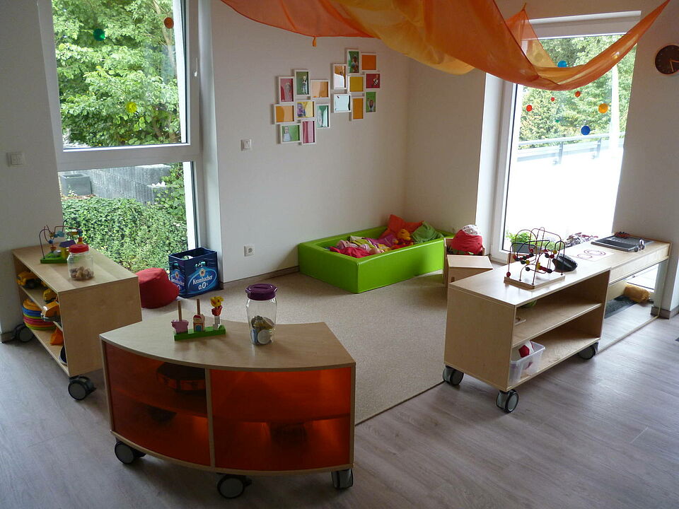 Rothemühler Knirpse_Gruppenraum Gruppenraum mit Spielecke und Schränken mit Spielzeug sowie Kuschelecke in einem bodentiefen Bettchen